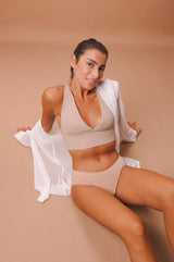 woman in beige period panty and crop top sitting on the floor